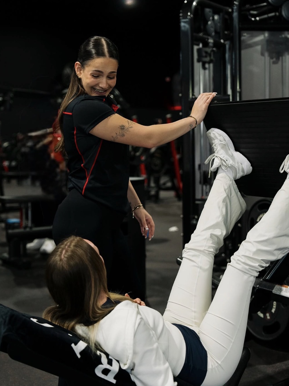 Dana spotting and encouraging a client on the leg press